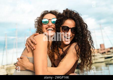 Zwei enge Freunde teilen sich eine Umarmung und ein Lachen auf einer Yacht und schätzen den Moment. Stockfoto