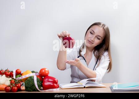 Lächelnde Ernährungswissenschaftlerin in ihrem Büro zeigt sie gesundes Gemüse und Obst, Gesundheit und Diät Konzept Stockfoto