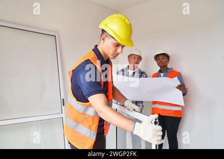 Zimmermann untersucht Fensterrahmen in der Nähe von Kollegen Stockfoto