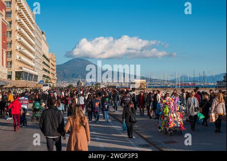 Neapel, Italien - 18. Dezember 2022: Eine geschäftige Menge von Touristen und Einwohnern, die vor einer majestätischen Kulisse des Vesuv-Vulkans spazieren Stockfoto