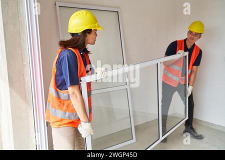 Junge Zimmerleute, die Fenster im Haus tragen Stockfoto