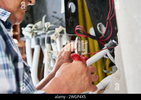 Leitender männlicher Elektriker, der beim Befestigen von Drähten eine Zange verwendet Stockfoto