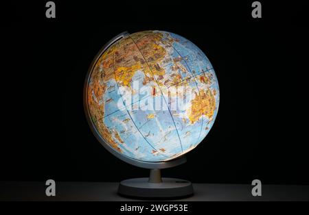 Beleuchtete Erdkugel in Form eines Nachtlichts auf dem Schreibtisch oder Tisch, das im Dunkeln leuchtet, keine Menschen. Stockfoto
