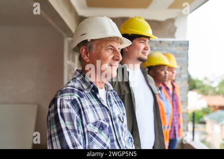 Leitender Auftragnehmer durch Kollegen, die Schutzhelme tragen Stockfoto