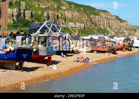 Menschen, die am Hastings Old Town Stade Fishing Boat Beach, East Sussex, Großbritannien, sonnen Stockfoto