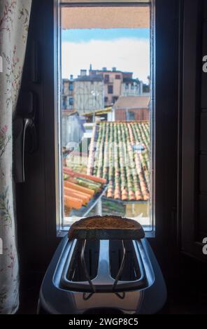 Toaster auf der Fensterbank eines Landhauses. Frisch zubereitete Scheibe über dem Rack Stockfoto