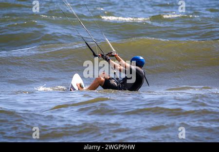 Ein Mann, der an ein Brett gezogen wird und eine Kite-Boarding-Fahrt im Atlantischen Ozean anfängt. Stockfoto