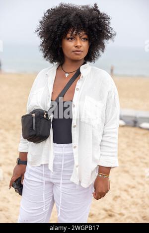 Ein Porträt einer jungen schwarzen Frau am Strand, sie schaut aus der Kamera. Stockfoto