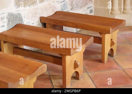 Reihen einfacher Holzbänke in einer kleinen Steinkapelle Stockfoto