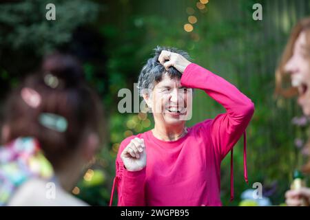 Eine reife Frau lacht mit Freunden und Familie auf einer Sommergartenparty Stockfoto