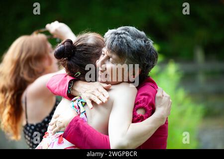 Eine Großmutter umarmt ihre Transenkelin auf einer Gartenparty Stockfoto