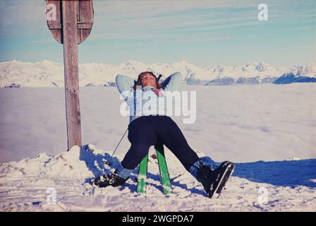 Skifahrer GER, 20240101, Aufnahme ca. 1966, Skifahrer in den Alpen, Mann sonnt sich auf einer Konstruktion aus Skistöcken und Ski, auf einer Bergkuppe über dem Nebel im Tal *** Skier GER, 20240101,Foto ca 1966, Skier in den Alpen, Mann sonnt sich auf einer Konstruktion aus Skistöcken und Skiern, auf einem Berggipfel über dem Nebel im Tal Stockfoto