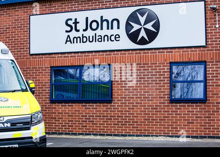 Blick auf das St. John-Ambulanzschild am Gebäude mit Teilsicht auf einen Ambulanzwagen Stockfoto