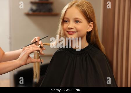 Professioneller Friseur schneidet Mädchenhaare im Schönheitssalon Stockfoto