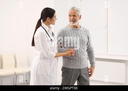 Lächelnde Krankenschwester, die ältere Patienten im Krankenhaus unterstützt Stockfoto