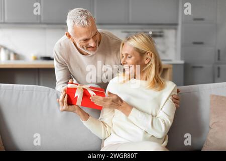 Liebevoller Seniorenmann, der seine Frau mit Valentinstag begrüßt Stockfoto