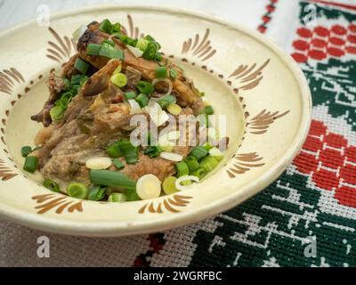 Ein weißer Teller mit Lammschale und frischen grünen Zwiebeln sowie zwei mit Fleisch gefüllten Tellern Stockfoto