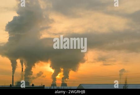 Industrielandschaft in Russland. Der Rauch aus der Kraft-Wärme-Kopplung steigt bei Sonnenuntergang sehr hoch an einem orangefarbenen Abendhimmel auf Stockfoto