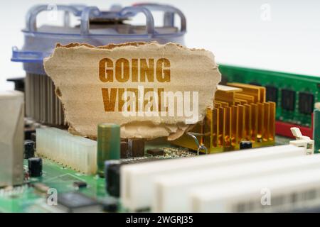 Auf dem Computermotherboard befindet sich ein Karton mit der Inschrift - Going viral. Computerkonzept. Stockfoto