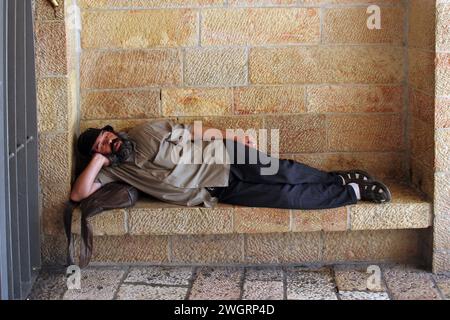 Ein Mann schläft auf einer Steinbank im alten Jerusalem, Israel Stockfoto