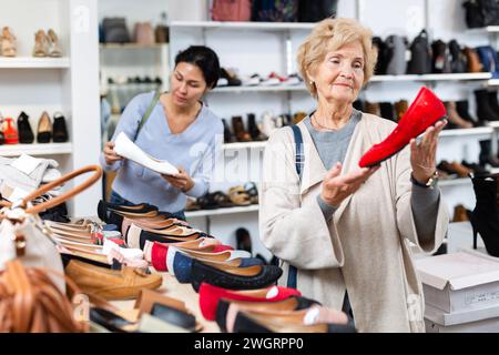 Verkäuferin hilft Oma bei der Auswahl neuer Schuhe Stockfoto