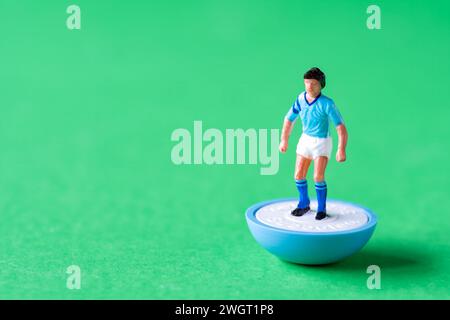 Eine einzelne Subbuteo Minifigur in den Farben der Manchester City FC Heimmannschaft mit himmelblauem Shirt, weißen Shorts und himmelblauen Socken. Stockfoto