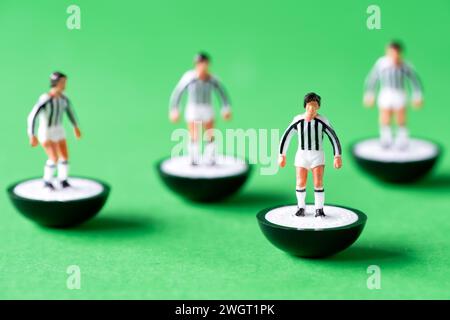 Eine Gruppe von Subbuteo Miniaturfiguren, die in den Farben des Juventus Teams mit weiß-schwarz gestreiften Hemden und weißen Shorts gemalt sind. Stockfoto