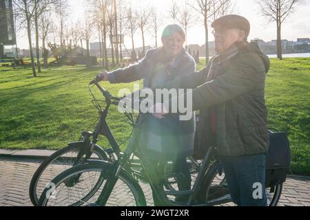 Ältere Paare, die eine Radtour machen, um fit und gesund in ihrem Ruhestand zu bleiben. Verwenden des Telefons, um nach Hause zu navigieren Stockfoto