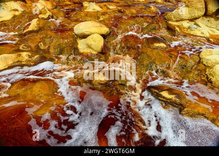 Schäumendes Wasser rauscht über die bunten, eisenbeladenen Felsen im Rio Tinto Stockfoto