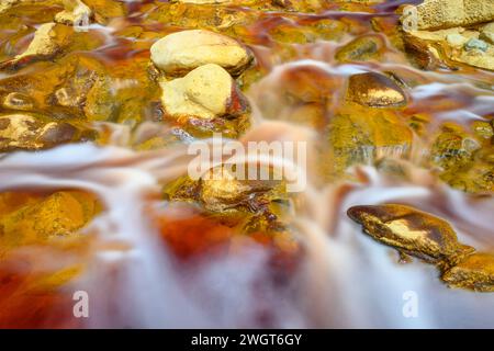 Schäumendes Wasser rauscht über die bunten, eisenbeladenen Felsen im Rio Tinto Stockfoto