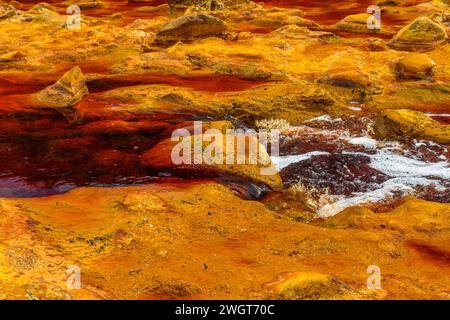 Schäumendes Wasser rauscht über die bunten, eisenbeladenen Felsen im Rio Tinto Stockfoto