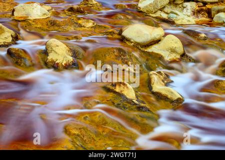 Schäumendes Wasser rauscht über die bunten, eisenbeladenen Felsen im Rio Tinto Stockfoto