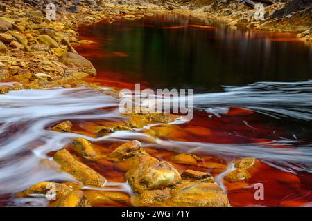 Schäumendes Wasser rauscht über die bunten, eisenbeladenen Felsen im Rio Tinto Stockfoto