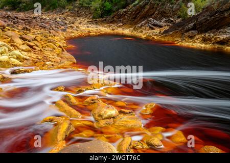 Schäumendes Wasser rauscht über die bunten, eisenbeladenen Felsen im Rio Tinto Stockfoto