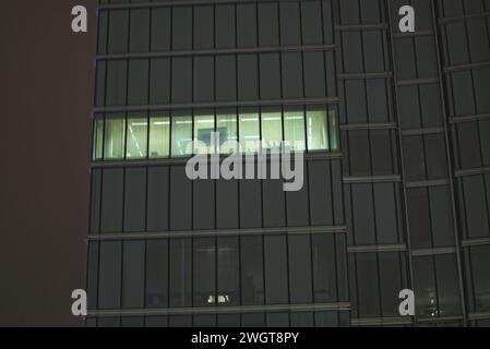 Brüssel, Belgien Februar 2024. Licht in einem der Wolkenkratzer in Brüssel. Hochhaus mit einer großen Glaskolik in der Nacht. Winterwetter Stockfoto