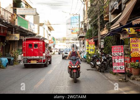 Frau mittleren Alters Alleinreisender, der einen Mietroller durch die Seitenstraßen von Chiang Mai fährt. Nordthailand Stockfoto