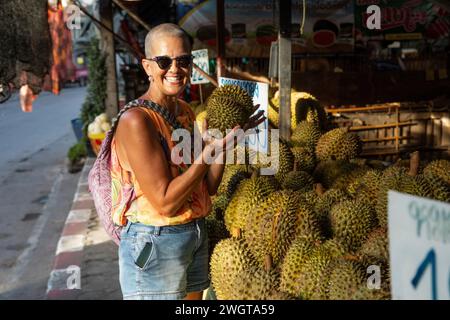 Alleinreisender mittlerer Alters schaut auf einem Markt in Nordthailand das lokale Obst und Gemüse. Stockfoto