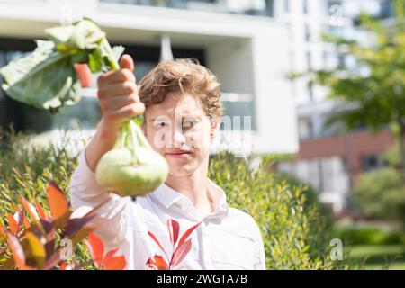 Junger Mann, der einen Kohl in der Hand seines Gartens hält Stockfoto
