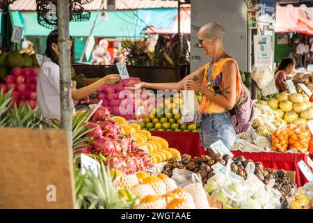 Alleinreisender mittlerer Alters schaut auf einem Markt in Nordthailand das lokale Obst und Gemüse. Stockfoto