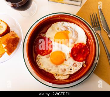 Beliebtes spanisches Gericht, Spiegeleier mit Chorizo-Würstchen und Tomatenpaste auf Teller Stockfoto