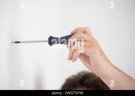 Die Hand eines Mannes, der eine Schraube mit einem Schraubenzieher einsetzt Stockfoto
