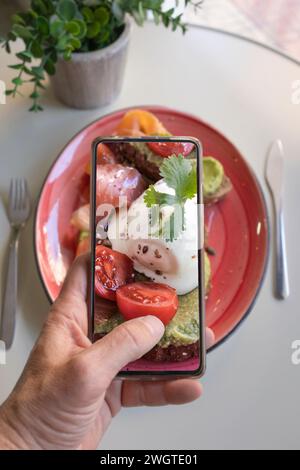 Smartphone-Fotos von vegetarischem Mittagessen oder Brunch. Die Hände eines Mannes machen Fotos von Lebensmitteln in modernem Stil für soziale Netzwerke oder Blogs. Stockfoto