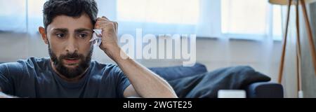 Ängstlicher Mann in lässigen Haushaltswaren mit Bart, die an Zusammenbruch leiden, geistiges Gesundheitsbewusstsein, Banner Stockfoto