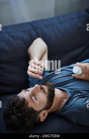 Schlecht depressiver Mann mit Bart, der Pillen während depressiver Episode nimmt, geistiges Gesundheitsbewusstsein Stockfoto