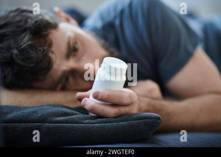 Verzweifelter Mann, der Pillen während depressiver Episode mit Selbstverletzung hält, geistiges Gesundheitsbewusstsein Stockfoto