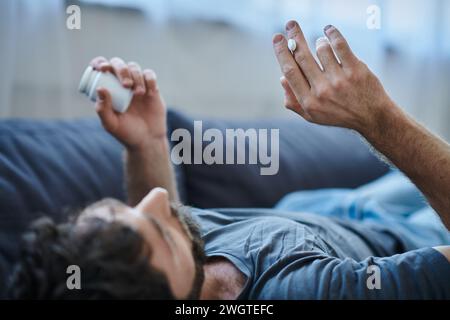 Schlecht depressiver Mann mit Bart, der Pillen während depressiver Episode nimmt, geistiges Gesundheitsbewusstsein Stockfoto