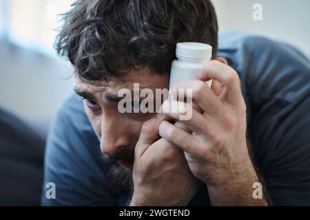 Verzweifelter Mann, der Pillen während depressiver Episode mit Selbstverletzung hält, geistiges Gesundheitsbewusstsein Stockfoto