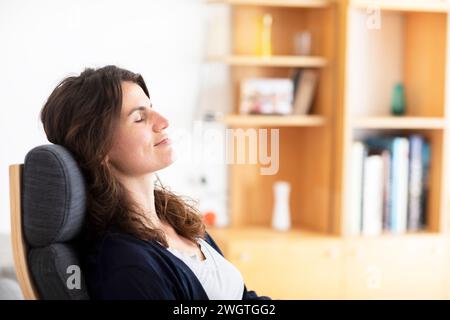 Junge Frau, die zu Hause sitzt und den Moment genießt Stockfoto