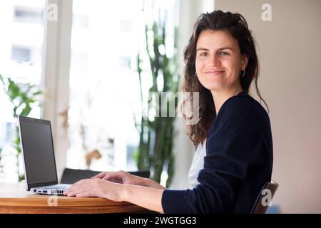 Junge Frau, die zu Hause mit grünen Pflanzen arbeitet Stockfoto