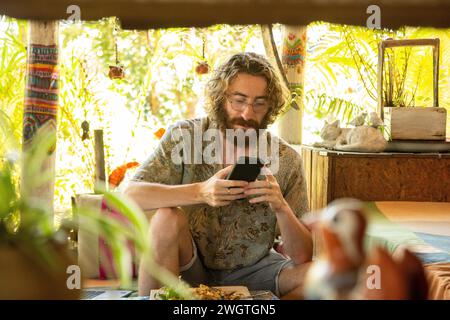 Junger Mann, ein Reisender, der sein Handy in einem Restaurant in Nordthailand benutzt Stockfoto